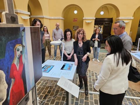 Un moment de la visita guiada a l'exposició, durant l'acte inaugural, davant d'una reproducció d'una pintura de Maties Palau Ferré