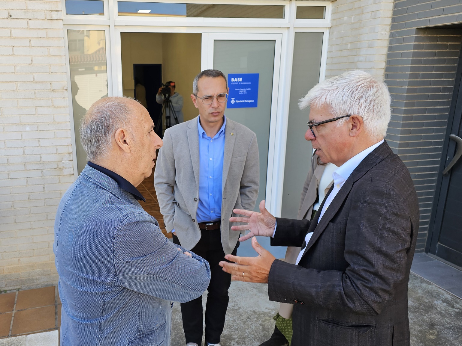 L'alcalde de l'Ampolla, el president de BASE i el cap d'aquest organisme, davant la porta del Punt d'atenció