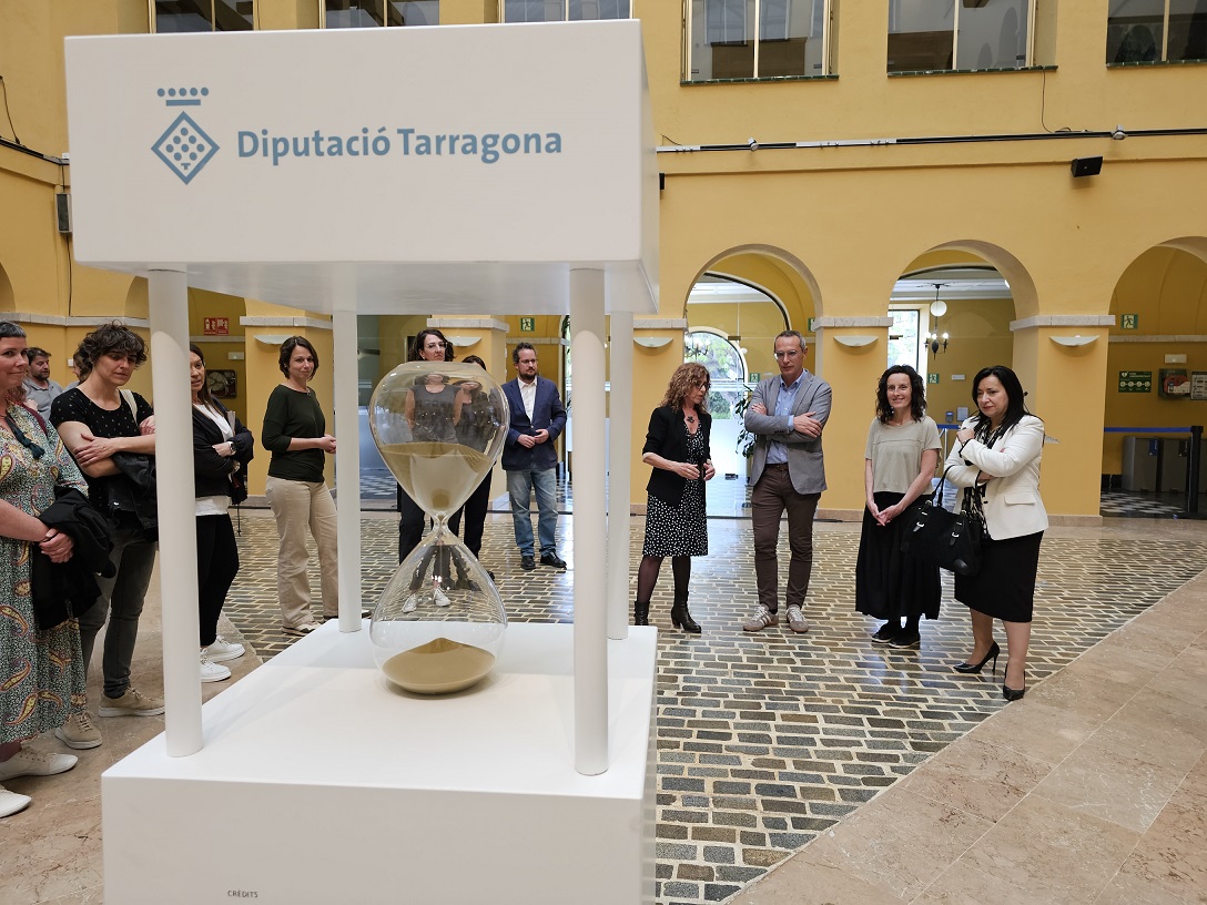 Un rellotge de sorra representa el caire efímer de les obres d'art i la necessitat de conservar-les